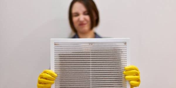 woman holding dirty dust ventilation grill
